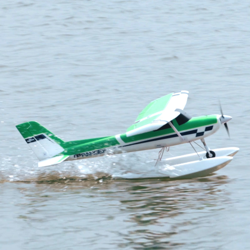 Green and white FMS 1220mm Ranger V2 RC airplane on water with floats.