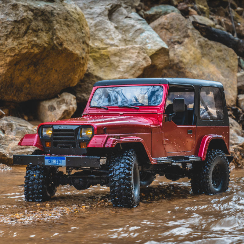 Muddy red 1:10 Mashigan RC rock crawler navigating rocky terrain