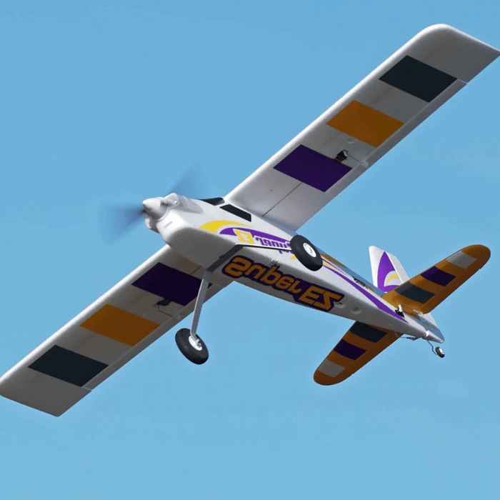 FMS Super EZ V4 RC airplane flying against a clear blue sky