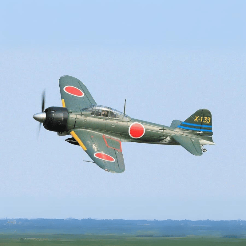 A6M3 Zero model flying with green body, red roundels, and blue tail stripes in clear skies