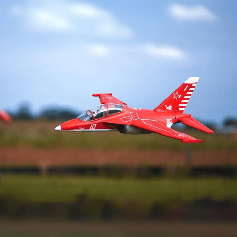 Vibrant red FMS Yak-130 V2 EDF jet in mid-flight against a blurred background